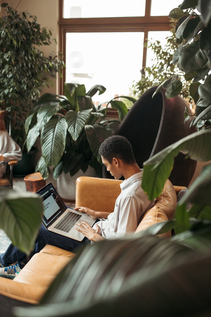 Diligent young professional working in a plant-filled modern office lounge.